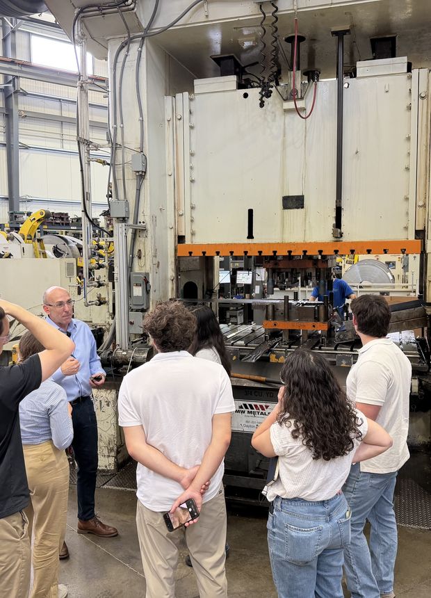 The cohort gathered at a stamping press at General Stamping and Metalworks